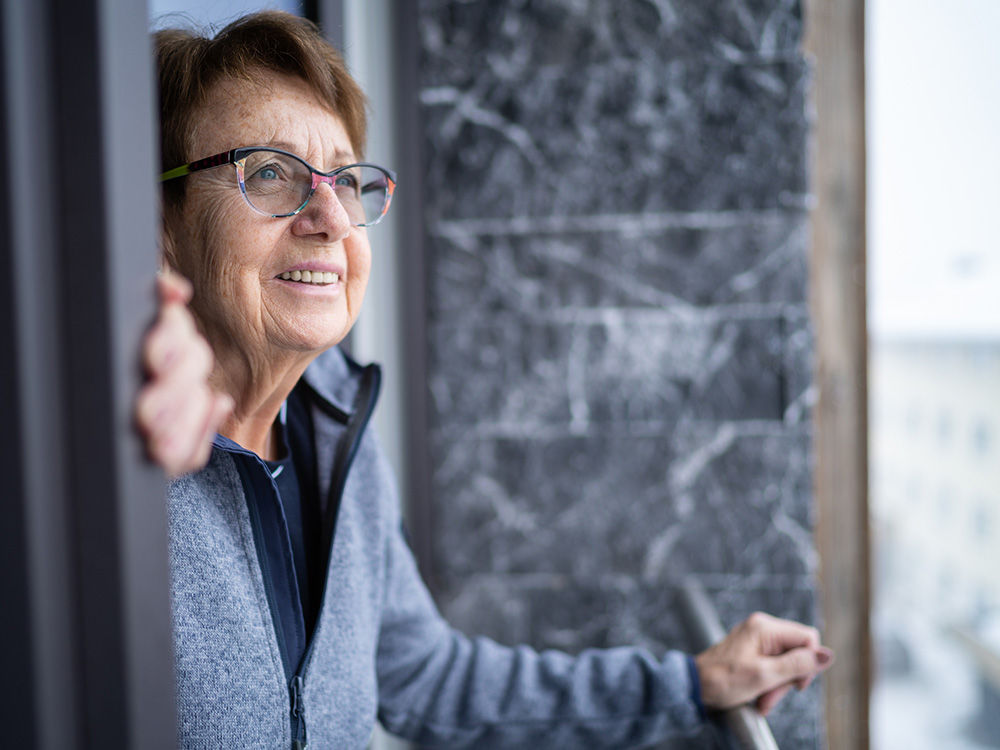 Senior woman looking outside her balcony