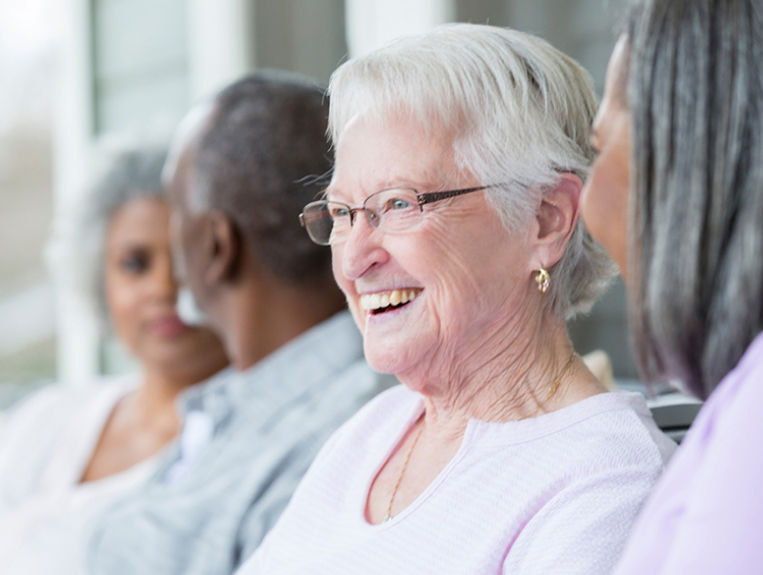 Senior woman laughing while sitting next to other older people