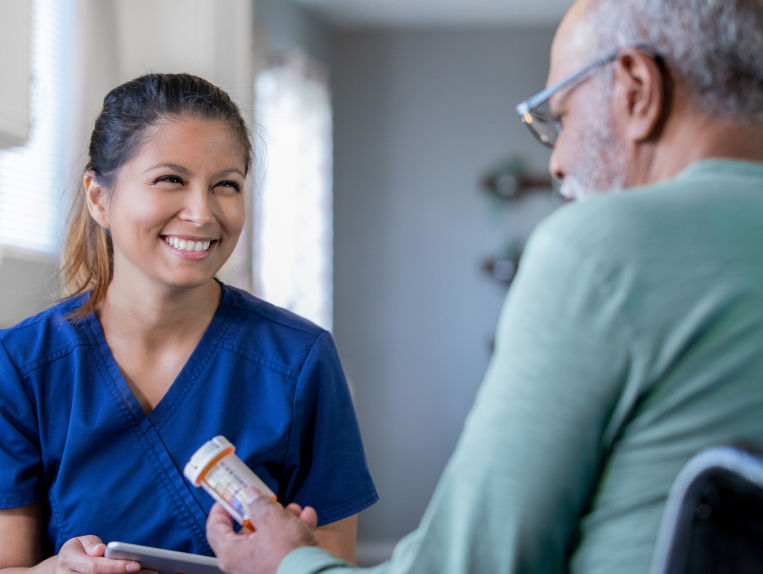 Nurse assists senior man with medication