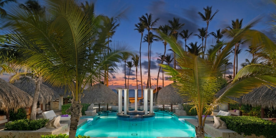 Luxury swimming pool with columns and palm trees at sunset at the Royal Service at Paradisus Palma Real resort in Punta Cana