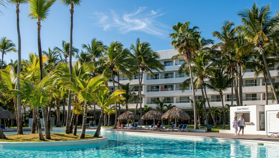 Instalaciones del hotel todo incluido Riu Naiboa en Punta Cana con vista a la piscina y palmeras tropicales.