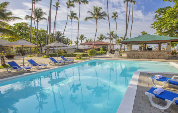 Piscina del hotel rodeada de palmeras y tumbonas