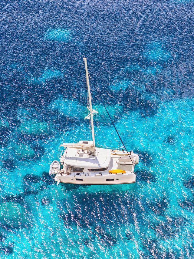 A bird view on a catamaran in blue, shallow water