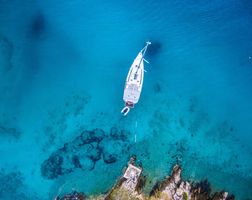 Sailboat attached to shore with mooring lines in blue water