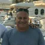 A man standing in front of yachts in a marina