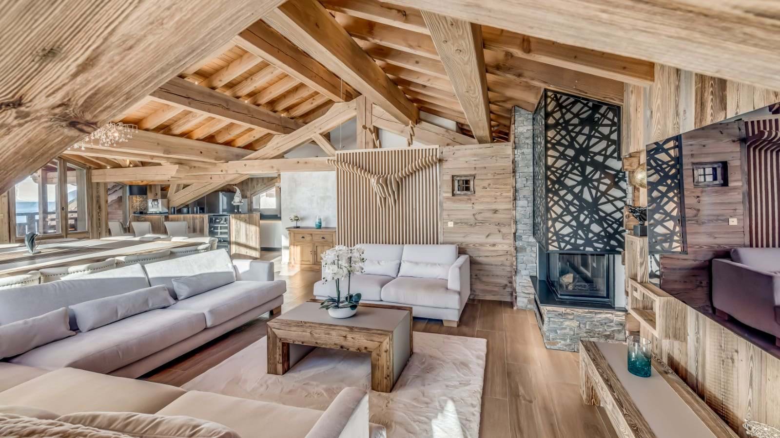 Open-plan living room with dual sectionals, wood-burning fireplace, and exposed beam ceiling