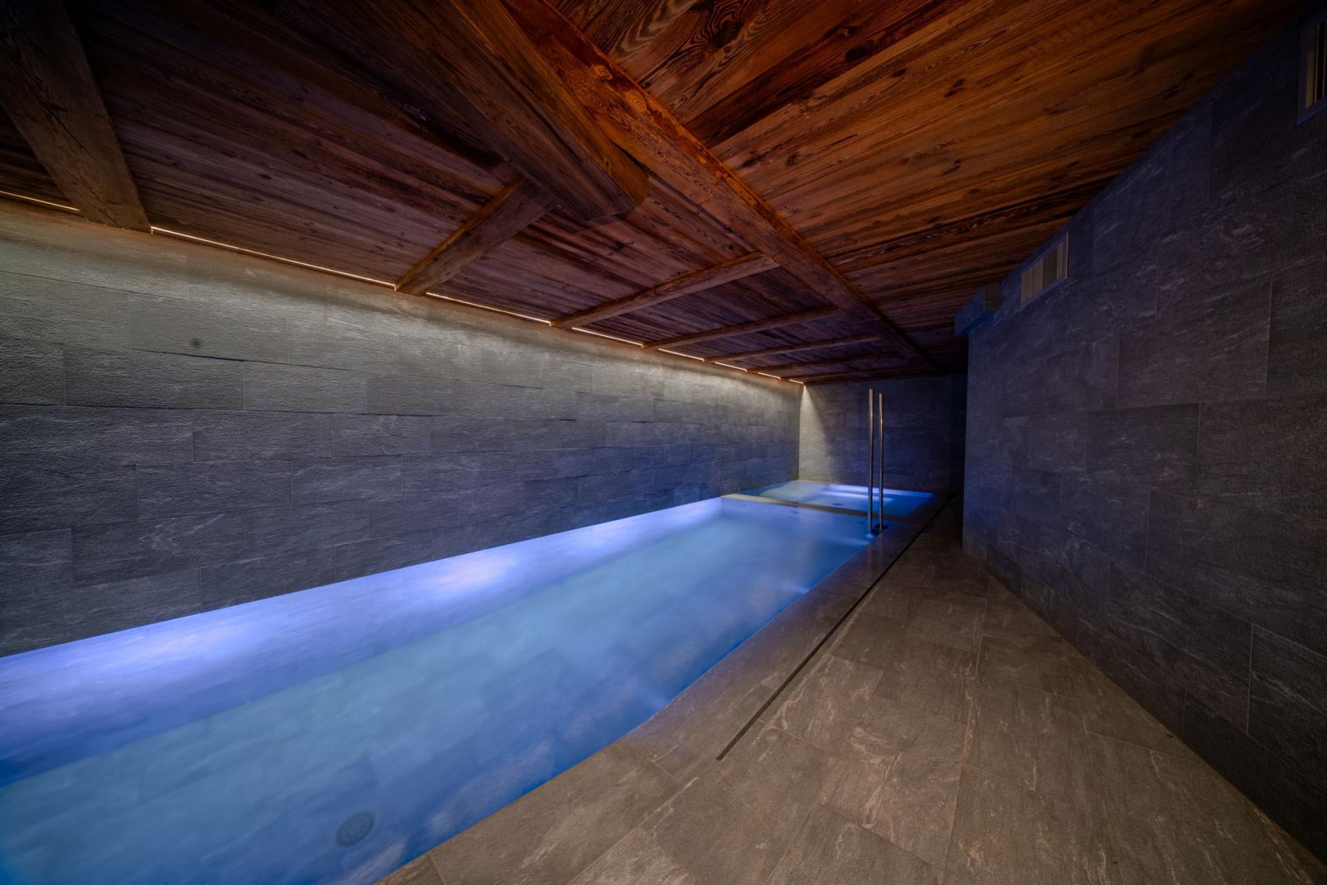 Indoor lap pool with wood-beamed ceiling and integrated spa area