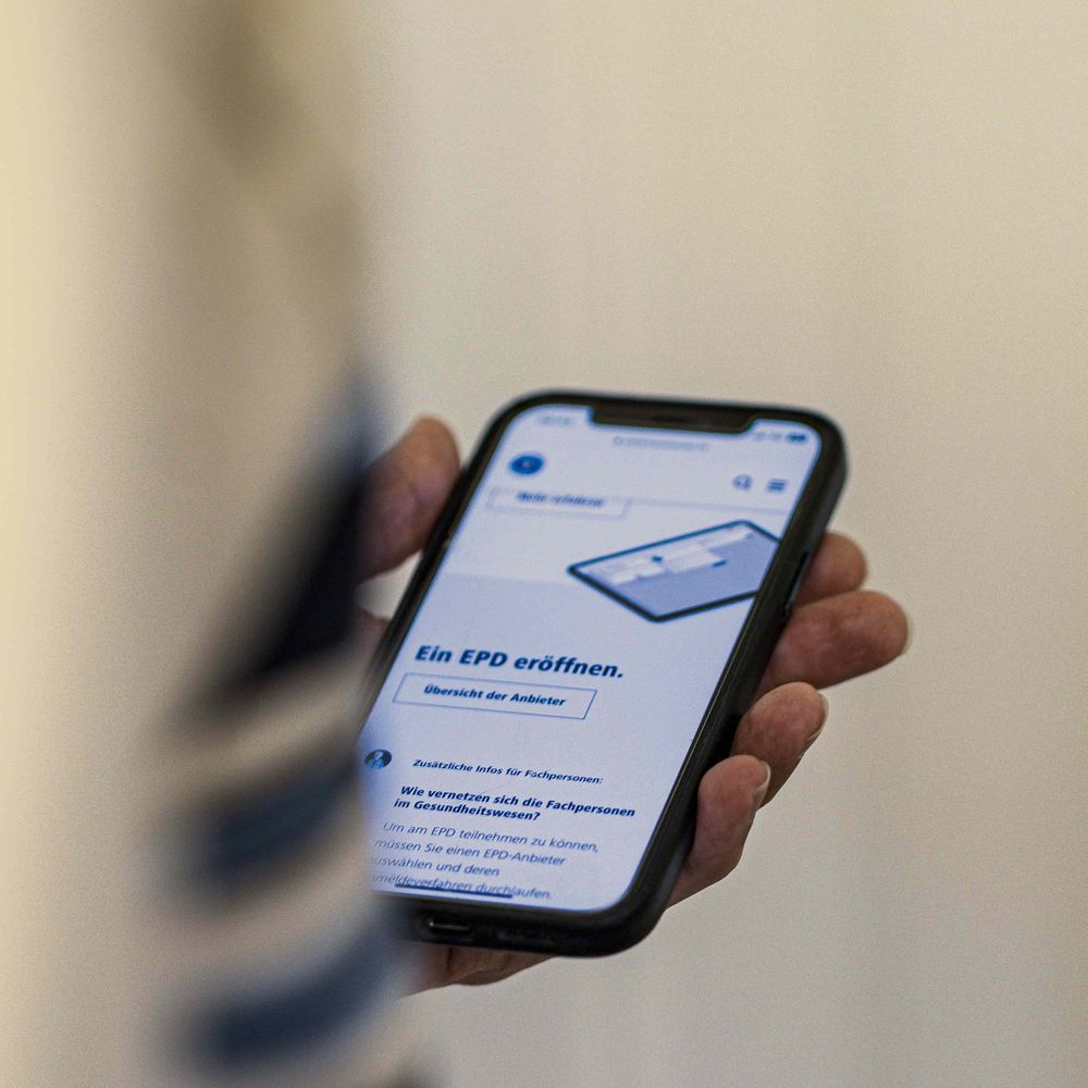 Ein Mitarbeiter von Zoebeli Communications hält ein Smartphone, das eine Seite zur Eröffnung eines EPD zeigt. Ein Mitarbeiter von Zoebeli Communications hält ein Smartphone, das eine Seite zur Eröffnung eines EPD zeigt.