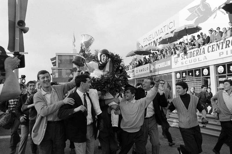 Race winner Jackie Stewart is carried through the pit lane after the podium celebration.