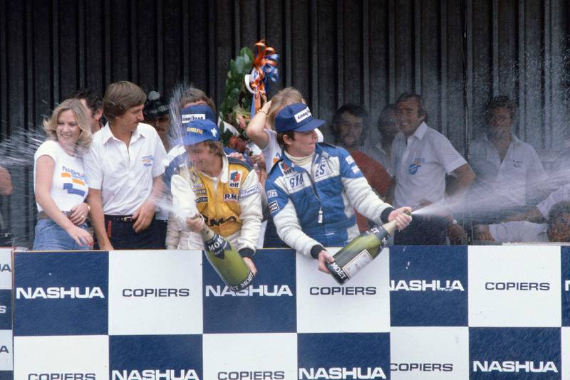 Rene Arnoux (Equipe Renault) celebrates his 1st position on the podium with Patrick Depailler (Ligier Ford) 3rd position.