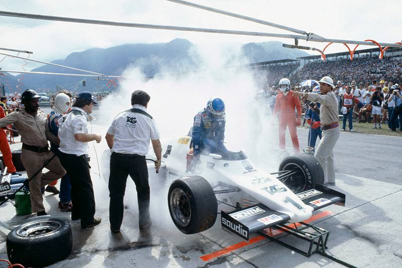 Keke Rosberg (Williams FW08C Ford) during a disastrous pitstop, where a small amount of spilt fuel caused a flash-fire which was promptly extinguished by marshals. He returned to his cockpit to finish 2nd but was disqualified for a push start after this stop.