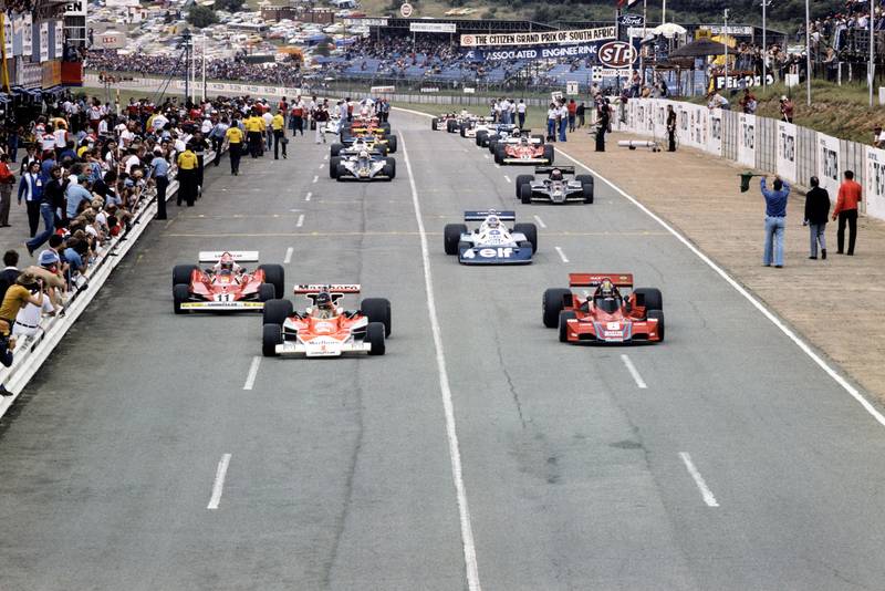 James Hunt (McLaren) and Carlos Pace (Brabham) contest the lead down to the first corner at the 1977 South African Grand Prix, Kyalami.