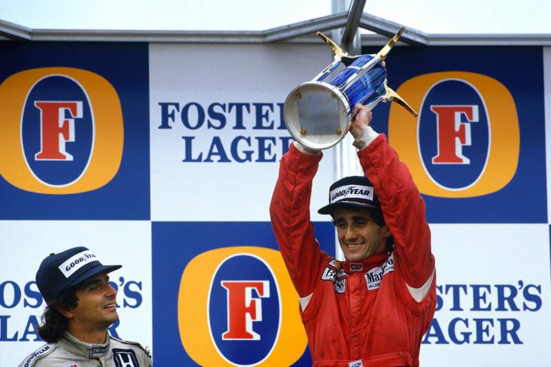 Alain Prost, 1st position, celebrates becoming World Champion again with Nelson Piquet, 2nd position, on the podium.