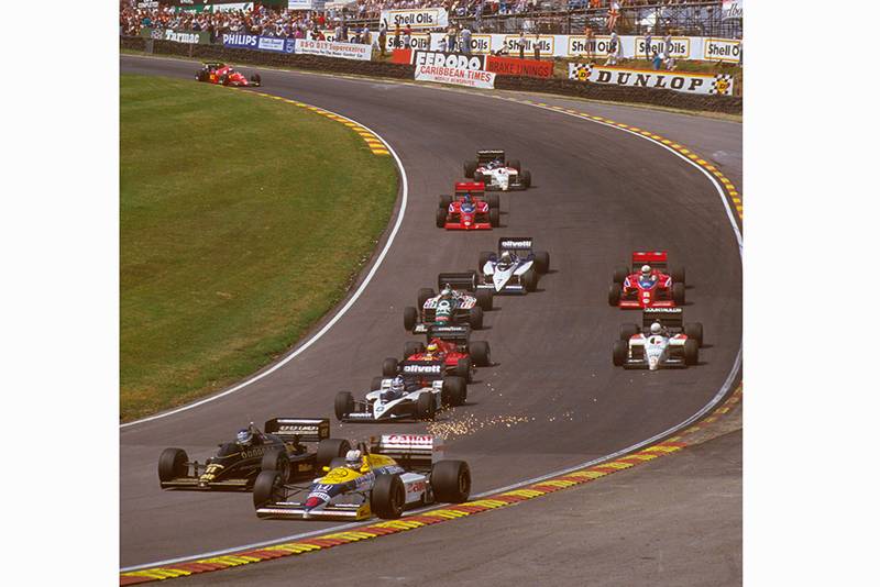 Nigel Mansell in 1st position exits Paddock Hill Bend ahead of the pack.