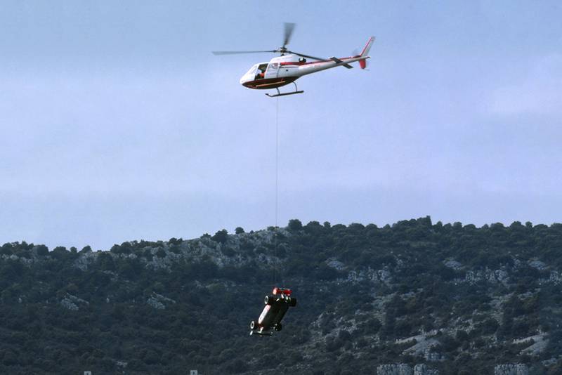 The Alfa Romeo 179C of Mario Andretti is lifted off the circuit by helicopter.