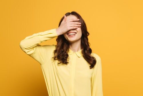 Frau hält sich lachend die Augen zu.
