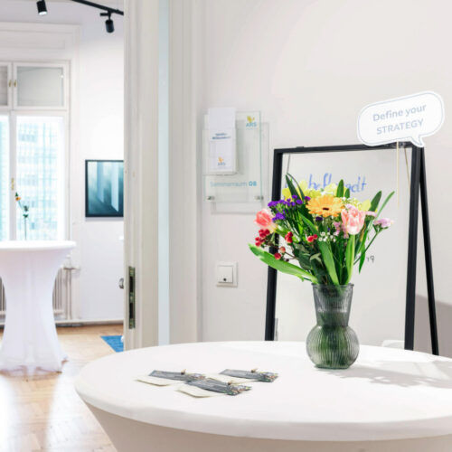 Stehtisch mit Blumenvase vor Seminarraum